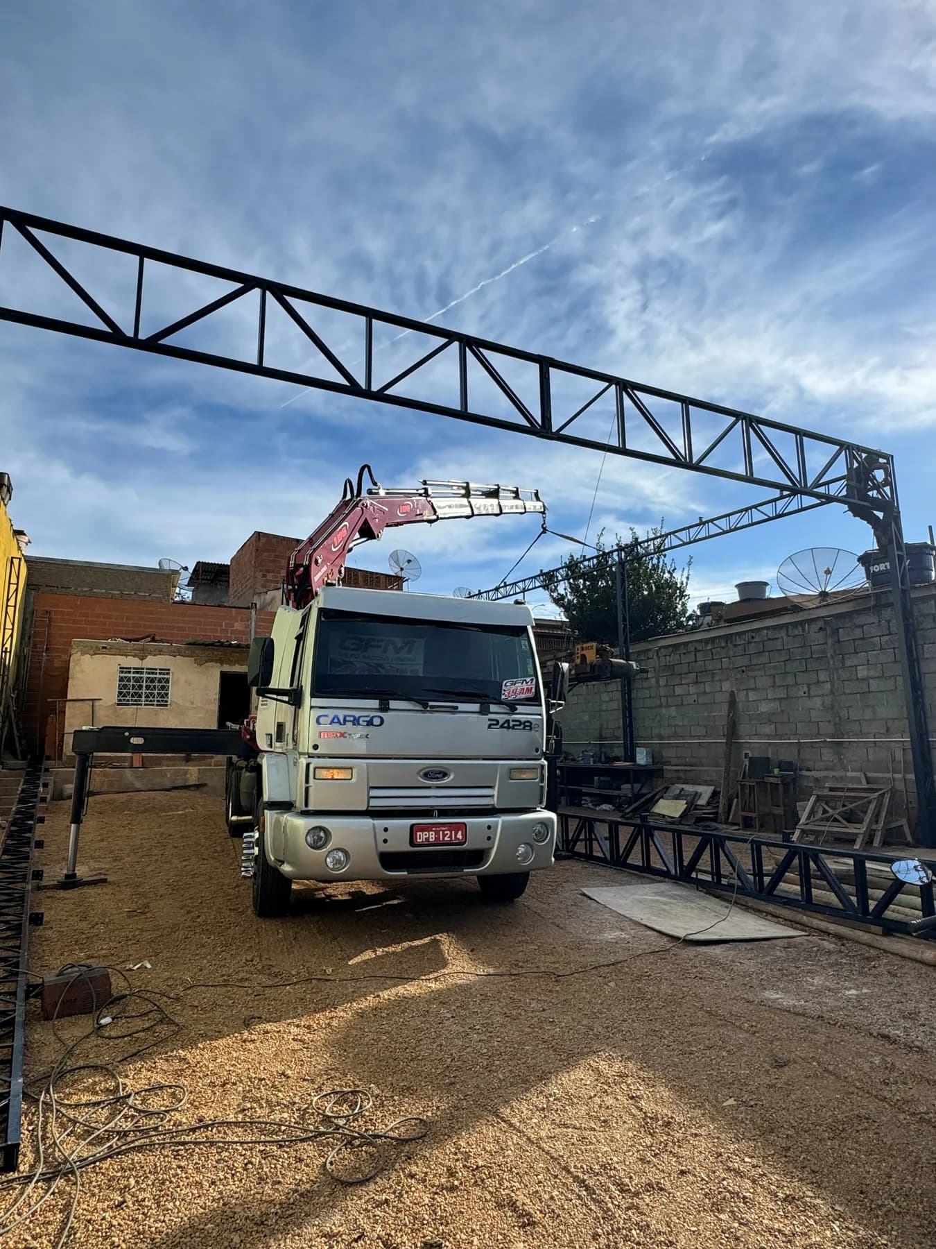Tesoura metálica de grande vão montada no pátio de fabricação, com o caminhão munck posicionado ao lado